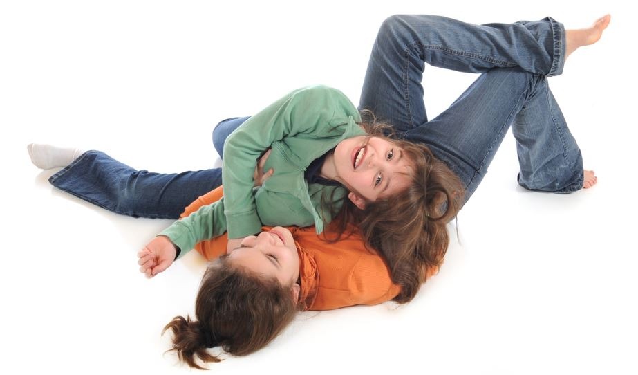 Two sisters on the floor in the middle of a fun fight.