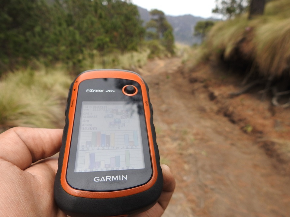 a person’s hand holding a gps while walking down a path