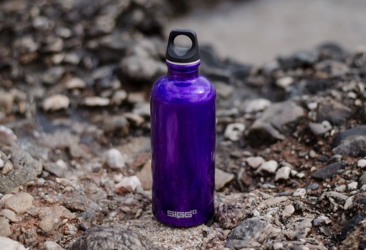a purple water bottle on gravel