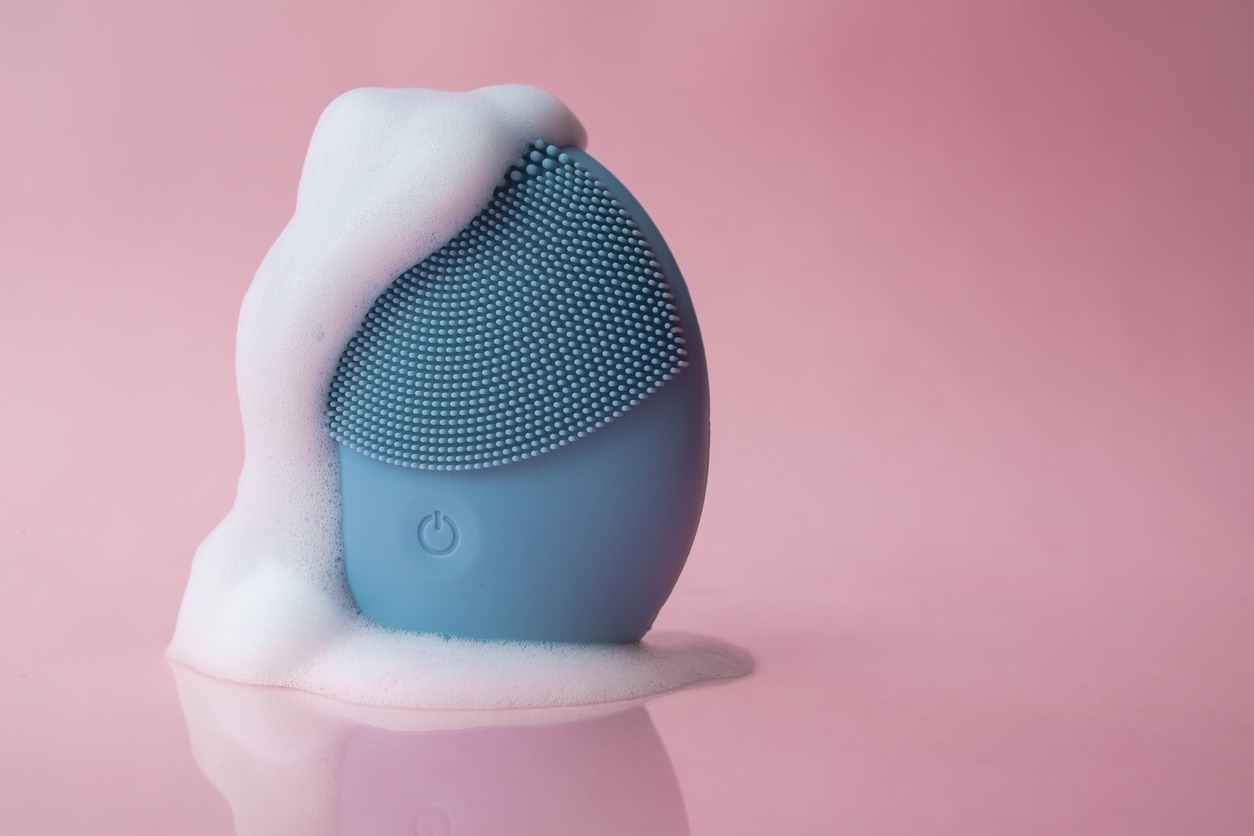 blue silicone face massager on a pink background