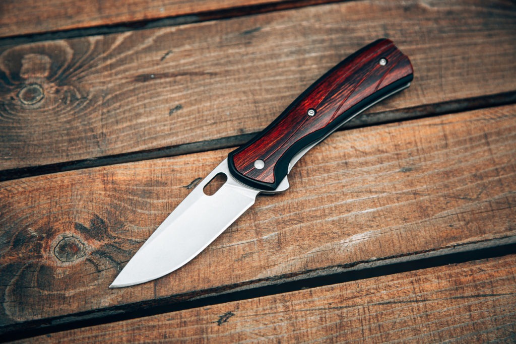 Folding pocket knife with wooden handle. A small knife on a wooden surface