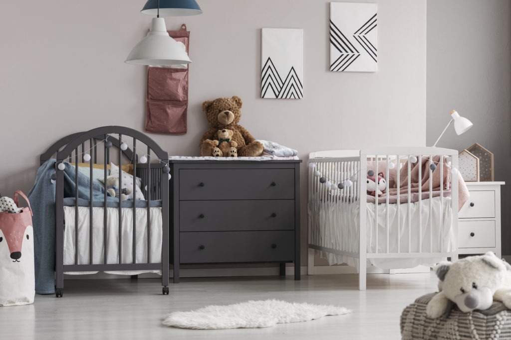 Grey wooden commode in the middle of cute baby room for twins