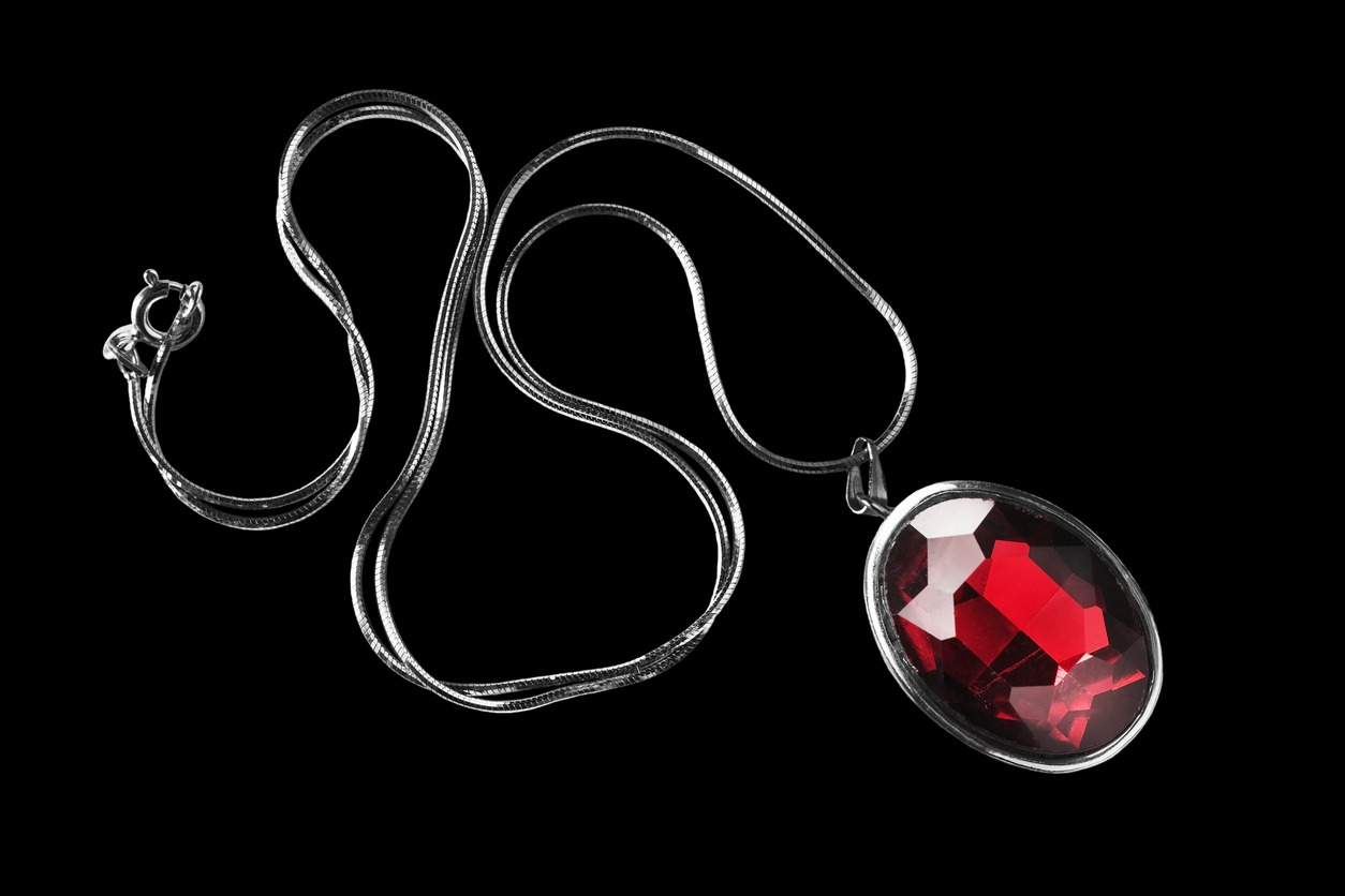 red ruby pendant in a silver chain on a black background
