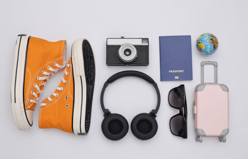 Stereo headphones, sneakers and travel accessories on white background. Top view