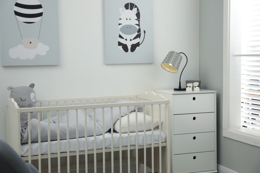 Stylish baby room interior with crib and chest of drawers