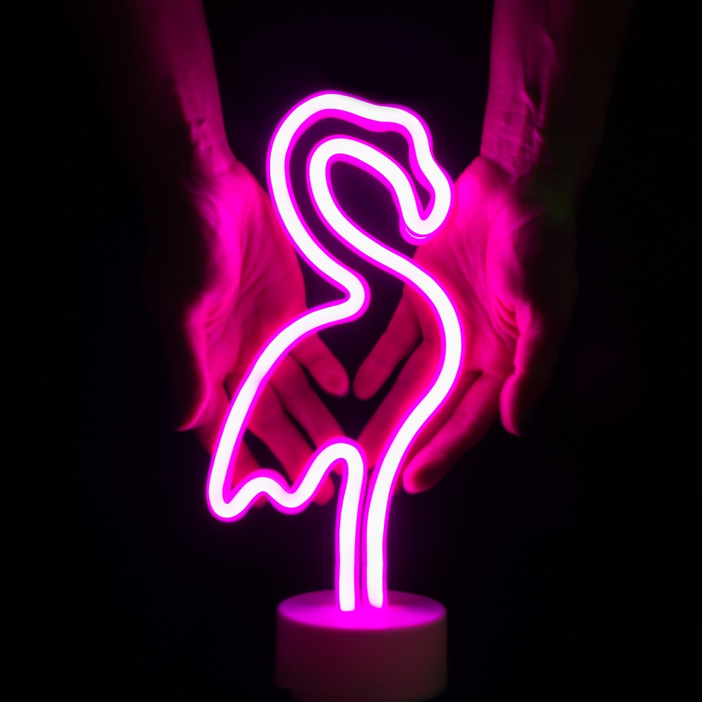 two hands holding a pink flamingo neon lamp