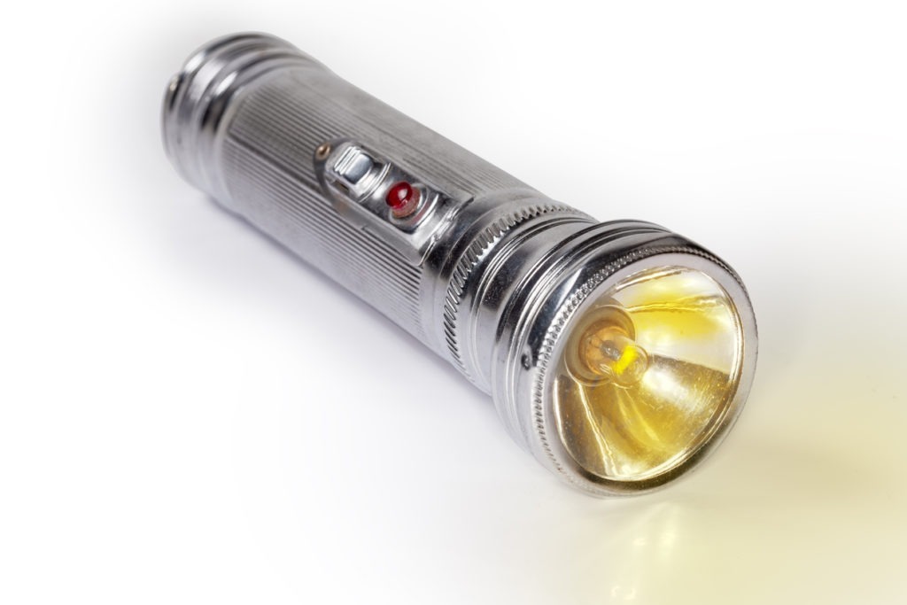 Vintage electric flashlight with incandescent lamp close-up, selective focus
