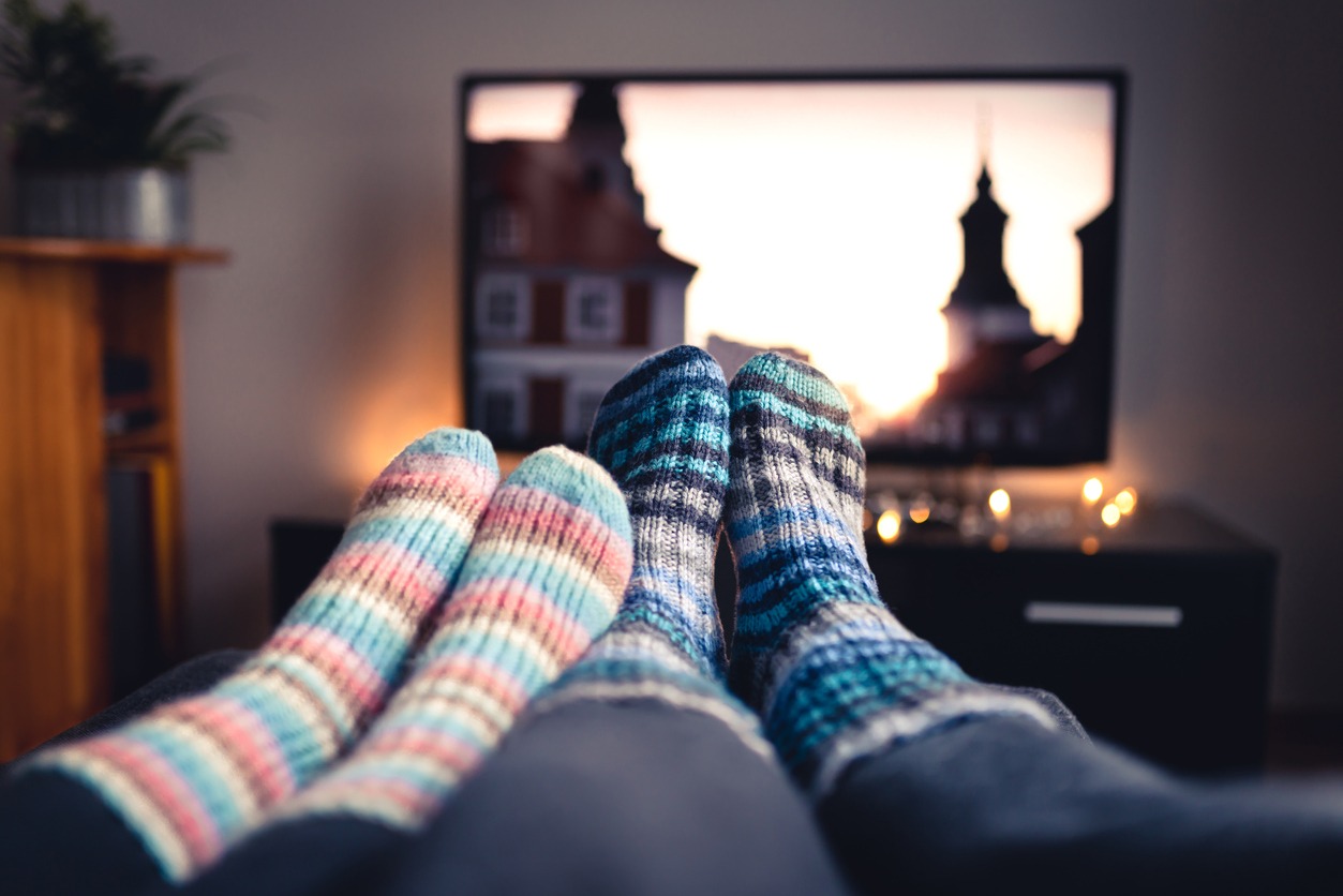 Couple with socks and woolen stockings watching movies or series on tv in winter.