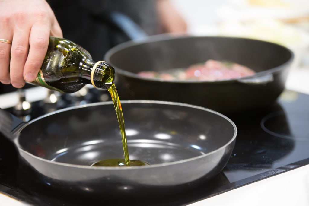 Drizzling cooking oil onto a frying pan. 