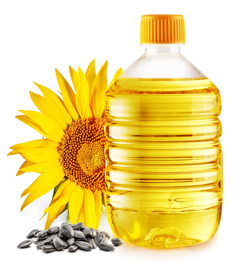 Sunflower seeds, a bottle of sunflower oil, and a white background. 