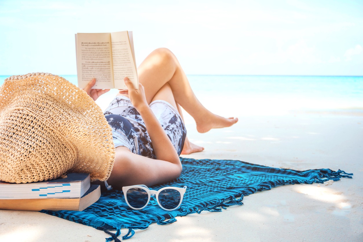 Woman reading a book on the beach in free time summer holiday stock photo