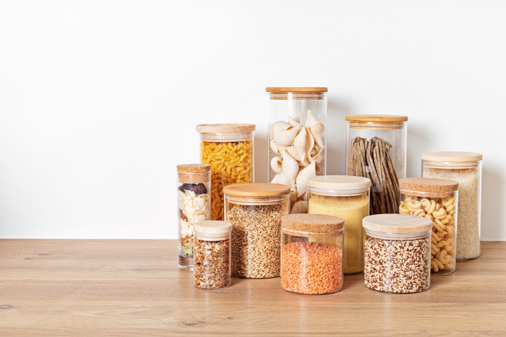  Assortment of grains, cereals, and pasta in glass jars on wooden table. Healthy balanced food ingredients, sustainable lifestyle, zero waste storage idea, eco-friendly concept