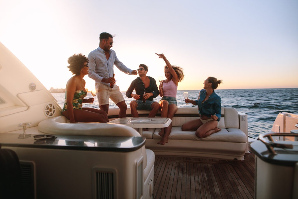 Group of happy friends having a boat party. Diverse men and women having drinks at sunset yacht parties and dancing