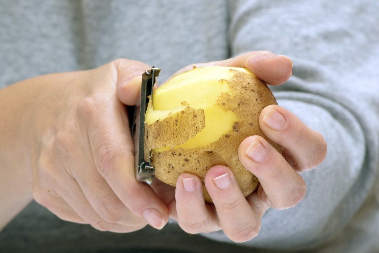 a closeup of a potato peeler while peeling a potato