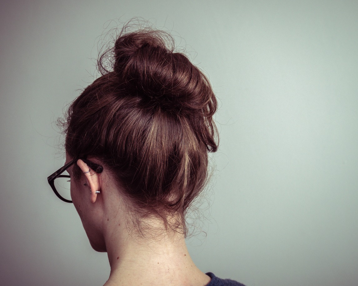 the back of the head of a woman with a messy bun hairdo