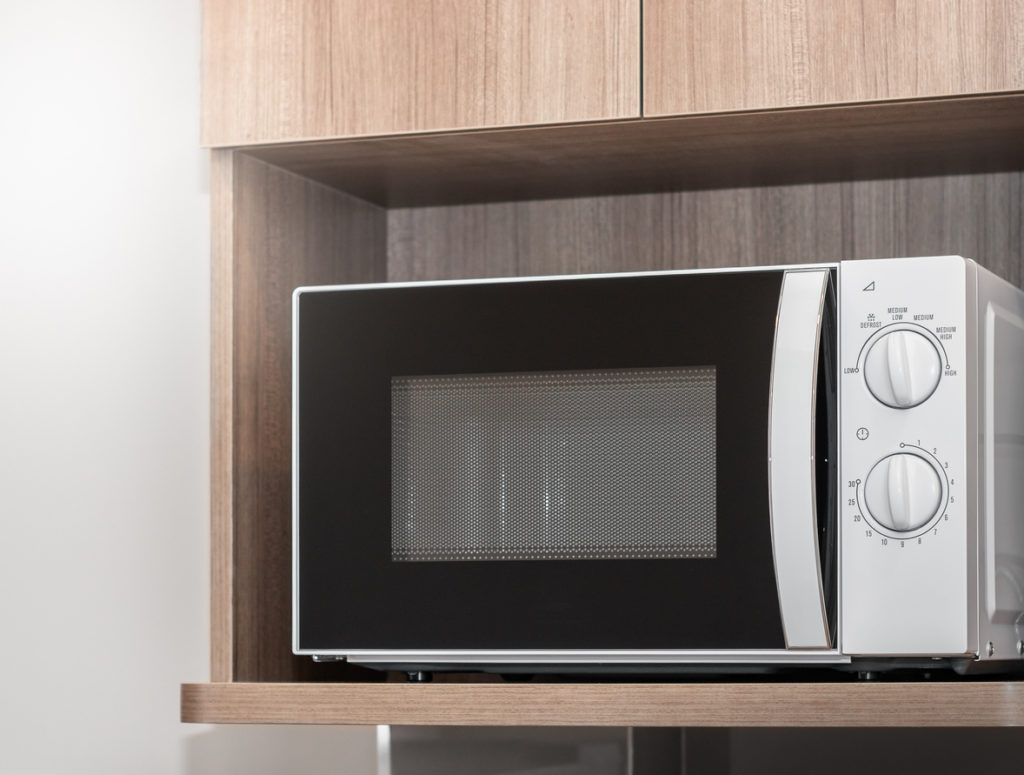 white microwave in a wooden shelf