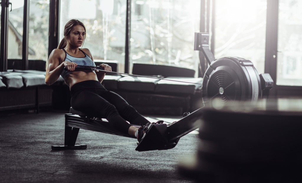 A woman using a rowing machine at the gym