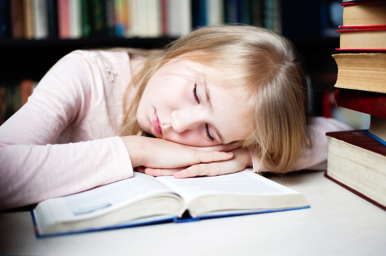 a girl sleeping on books spread around