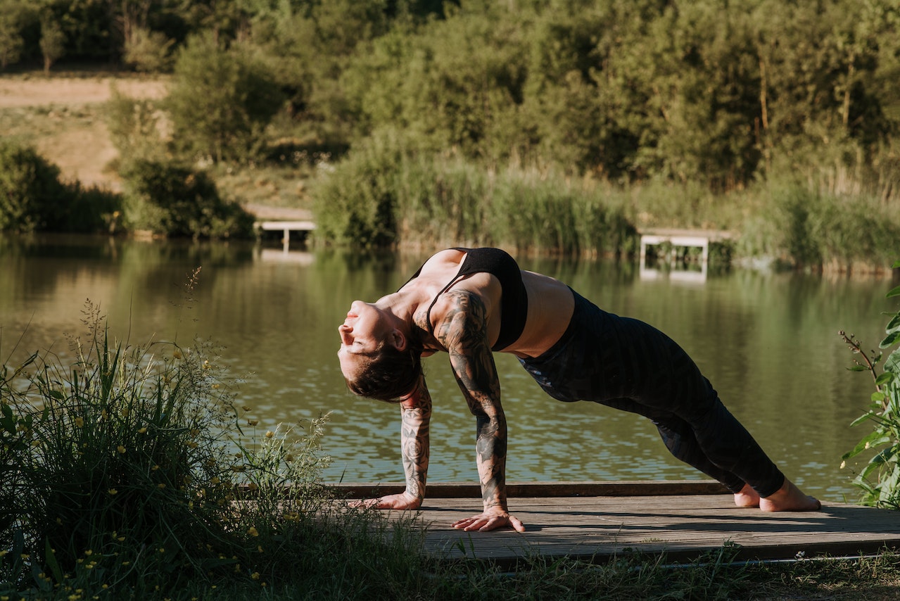 a woman doing yoga in front of a lake