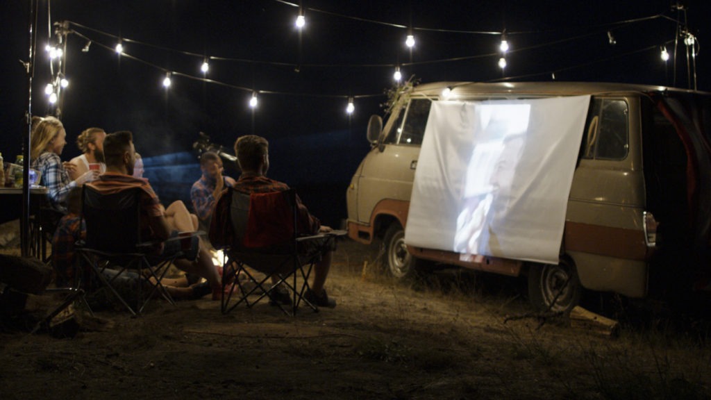 A group of friends watching a movie using a portable projector