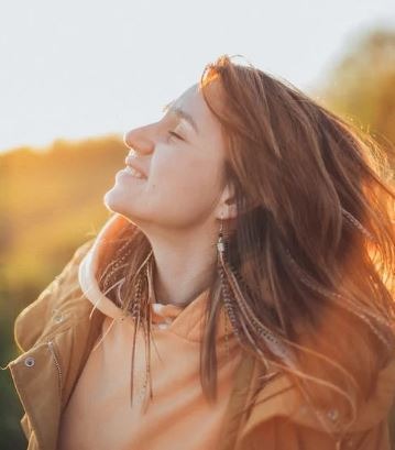 Young woman enjoying bright sun rays and fresh air