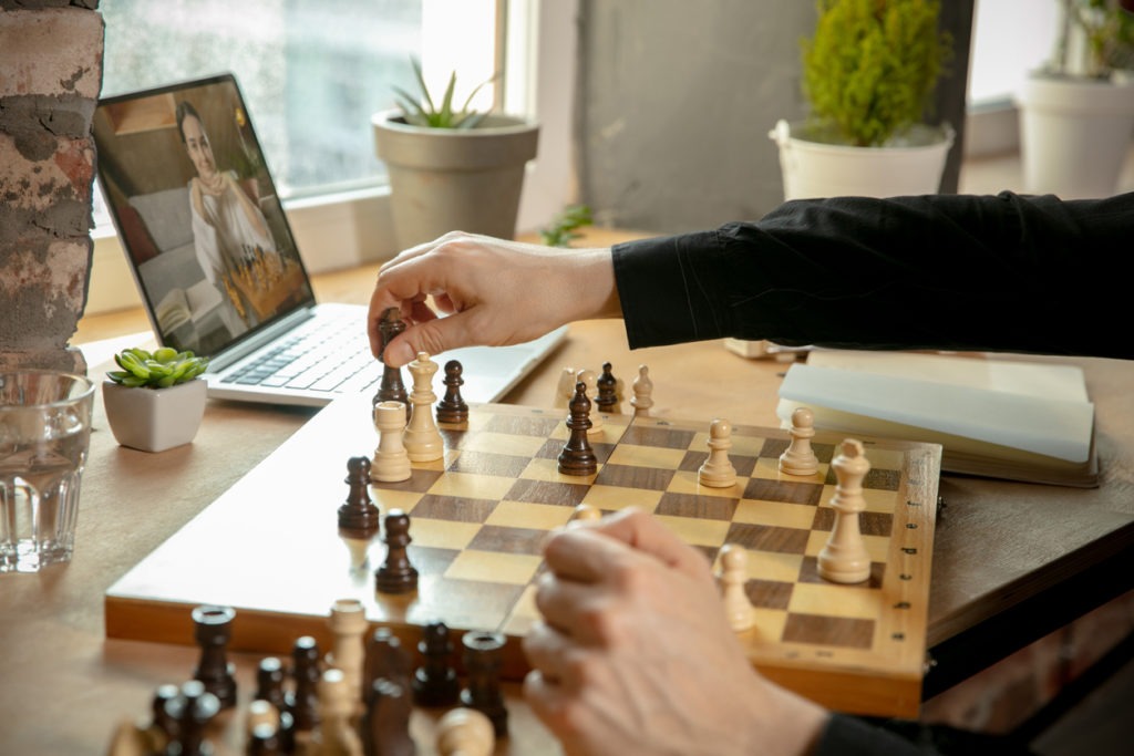 Close-up male hands playing chess online with young woman