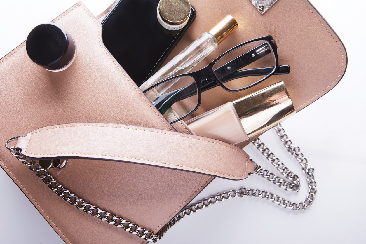 flat lay of female fashion accessories and pink handbag on white background