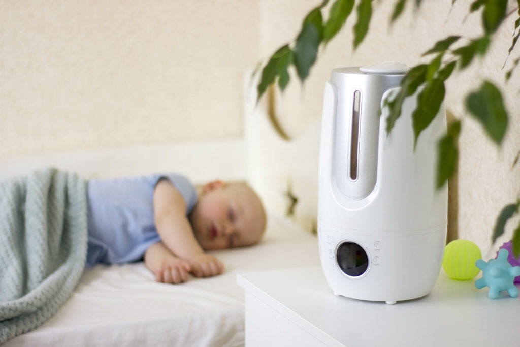 Cute little baby boy sleeping in bedroom with air humidifier