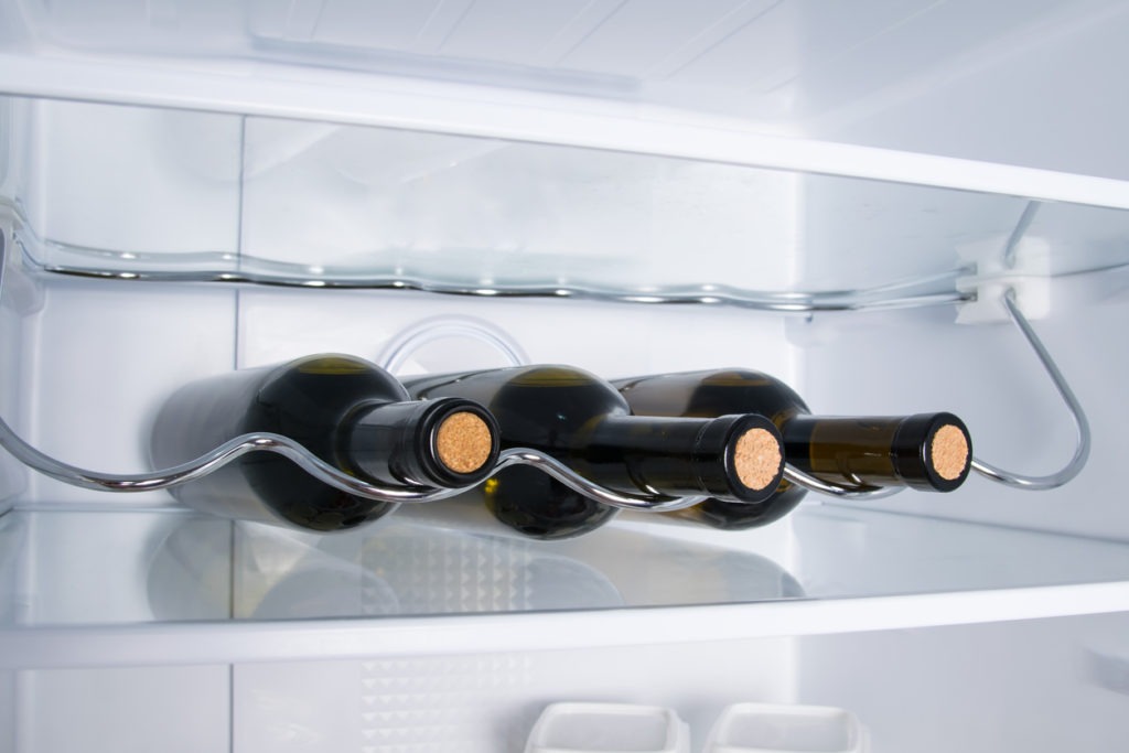 there are three bottles of wine on the shelf of the white refrigerator