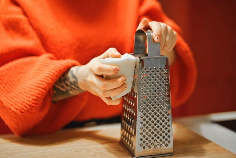 a person holding a grater and grating cheese