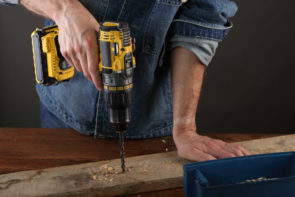 A battery-operated drill drilling a hole into a wood plank
