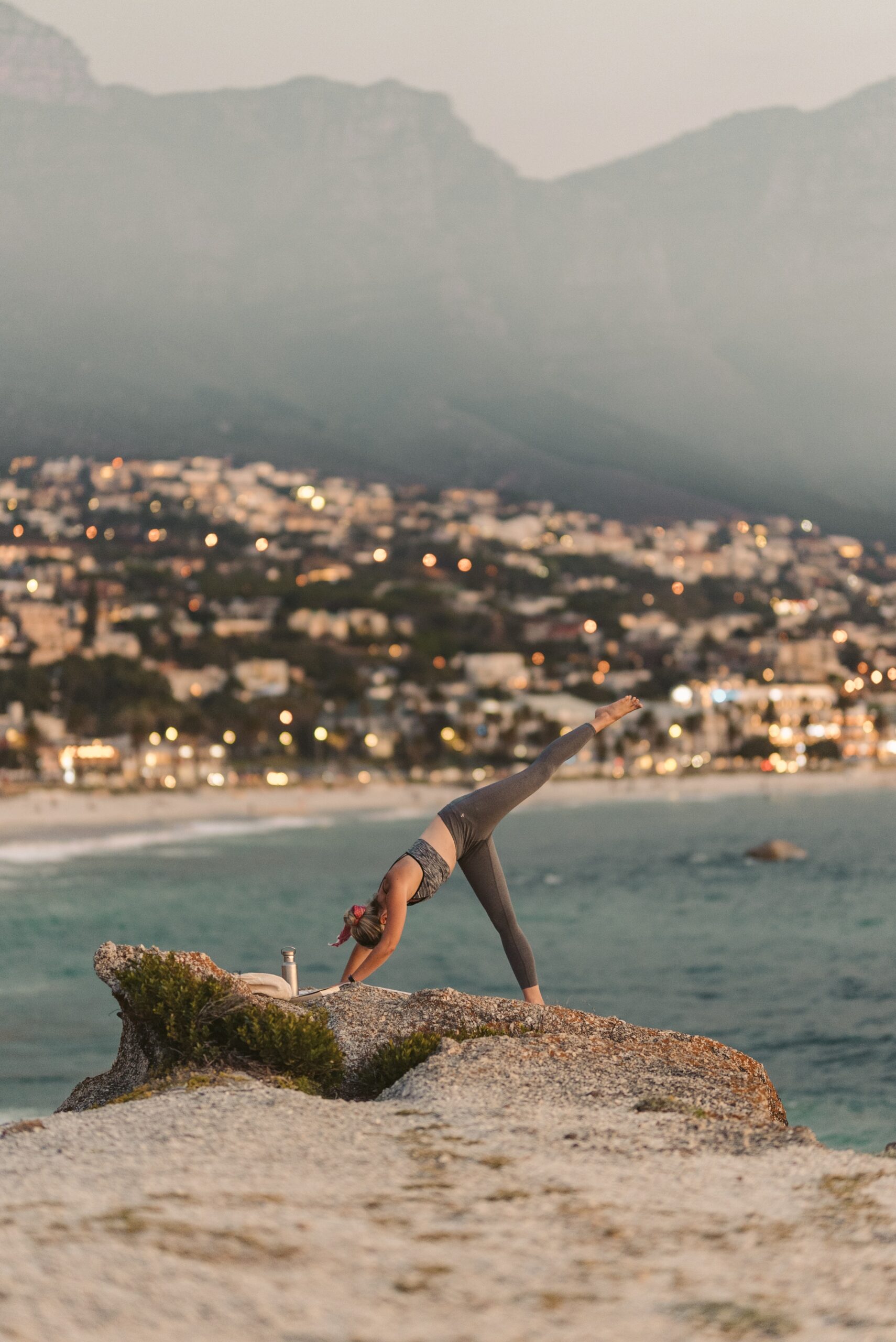 a woman doing yoga exercise under the sun on a beach