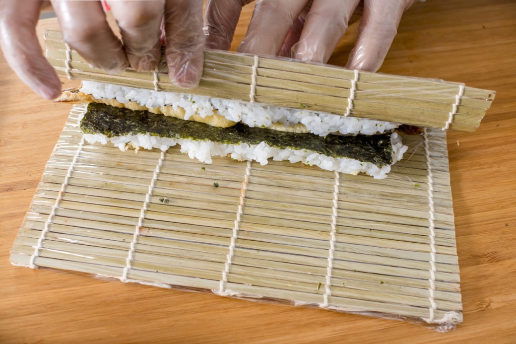 Using a Makisu to roll a batch of tempura maki. Wearing plastic gloves as health and safety protocols.
