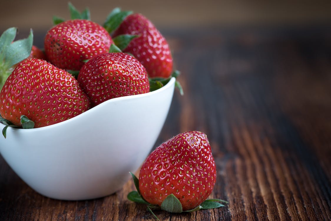 white bowl filled with whole strawberries