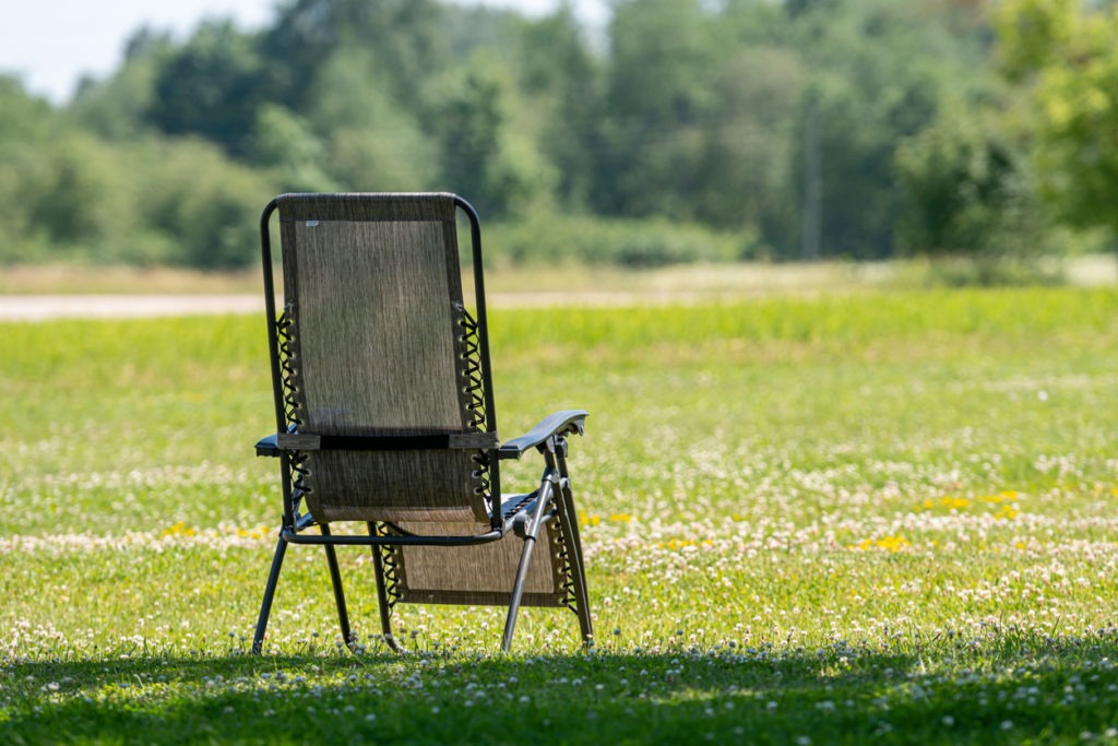 Empty folding garden chair on the yard lawn of a country house