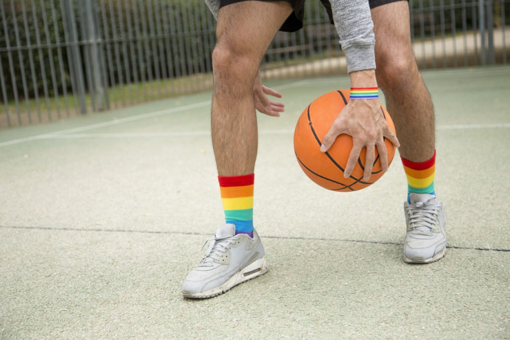 Basketball player in sneakers and rainbow socks dribbling with a ball on an outdoor court