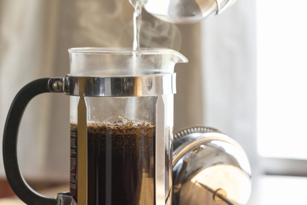 pouring water into french press with coffee grounds