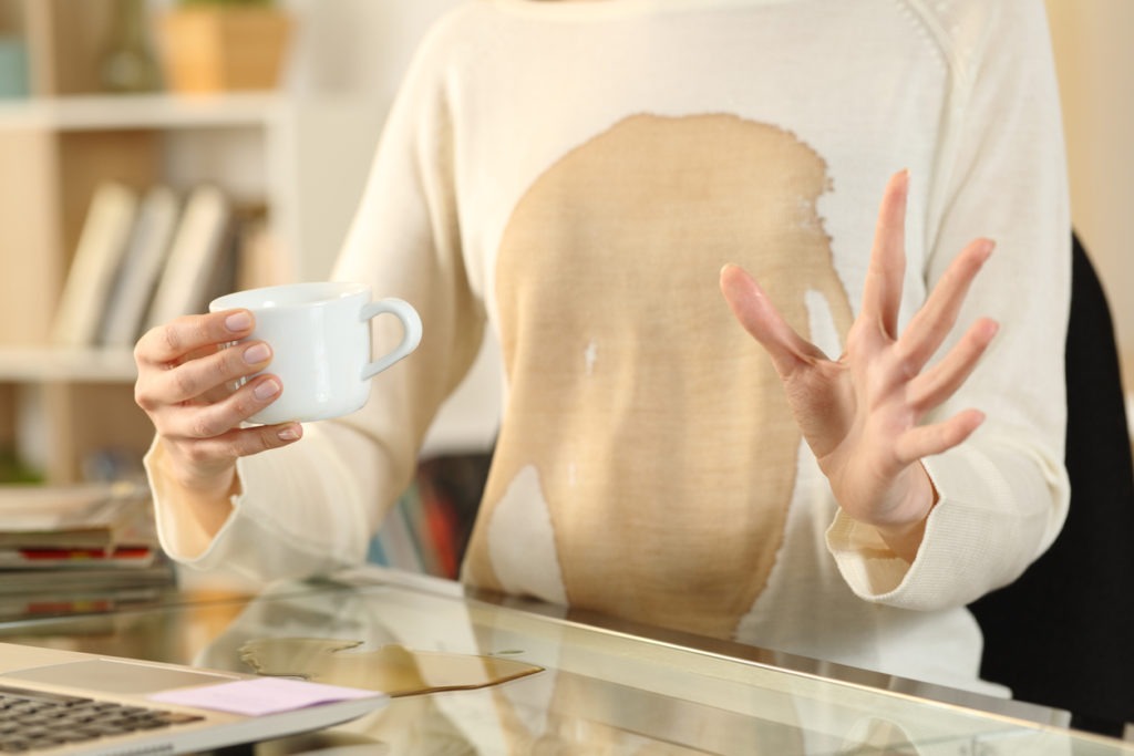 Woman hands with spilled coffee over her shirt