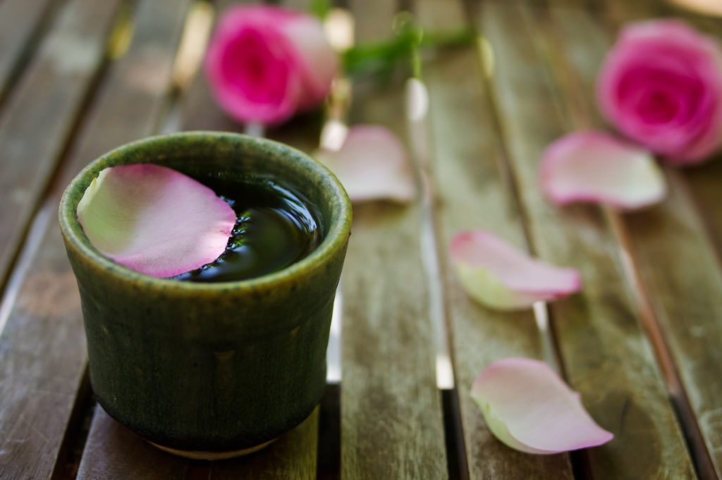 Petals-of-pink-rose-with-a-tea-cup-on-wooden-table