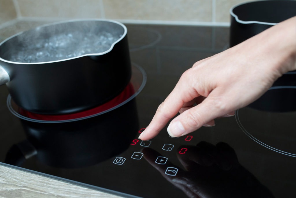  Close up of woman adjusting temperature of an induction cooker in the kitchen