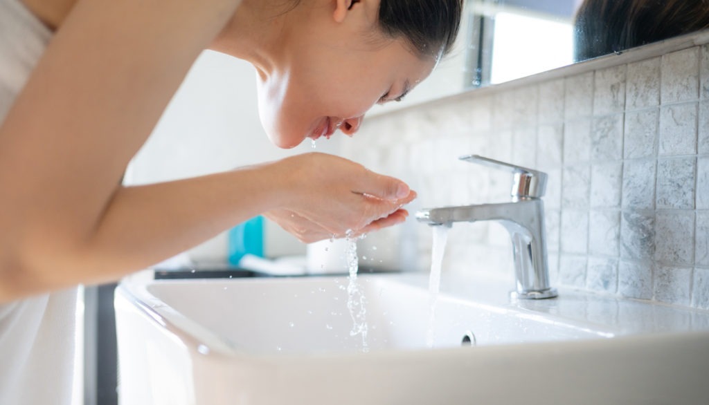 a woman washing her face in the sink