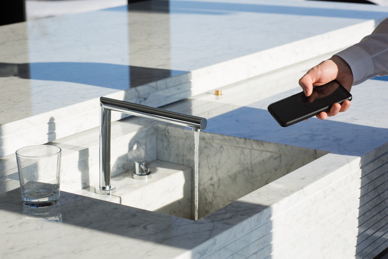 A man controls smart faucet using phone app