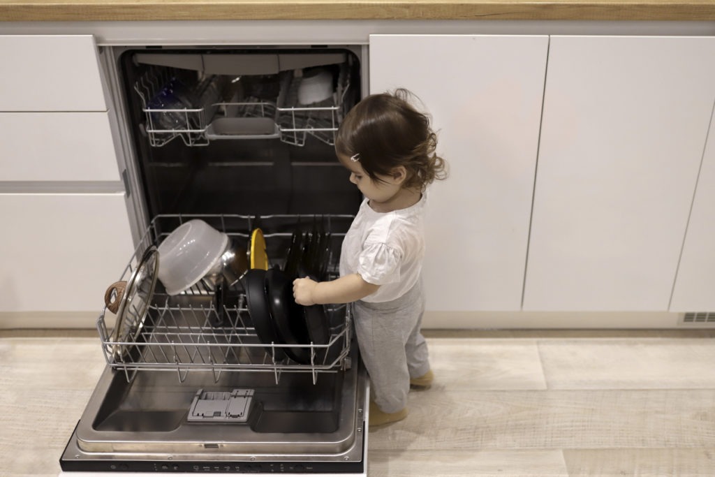 Little girl touching the dishwasher