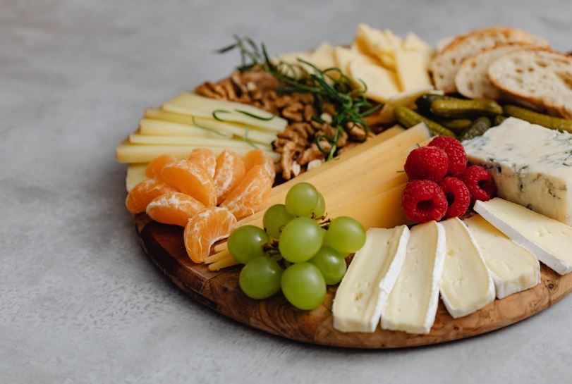 assorted fruits, cheeses, and bread on a round charcuterie board