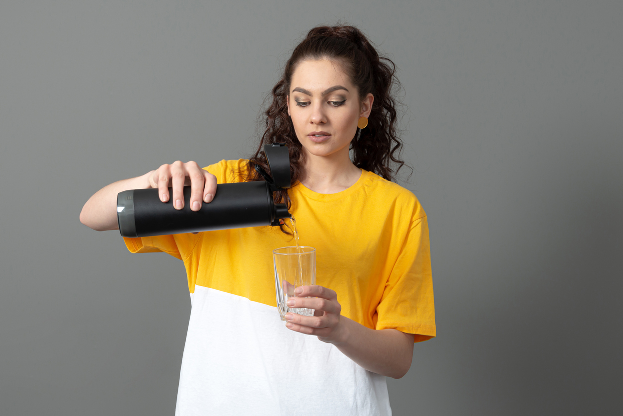 A woman pouring water from a smart water bottle into a glass
