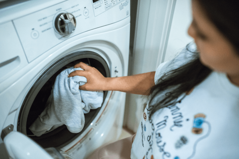 Woman putting clothes in a front load washing machine