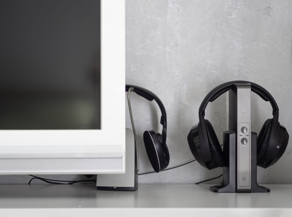 Wireless noise-canceling black headphones charging next to television