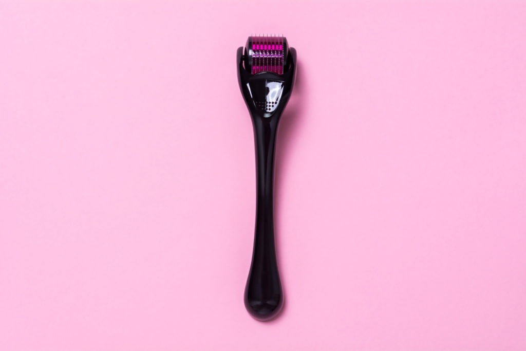 Image of a derma roller on a pink background