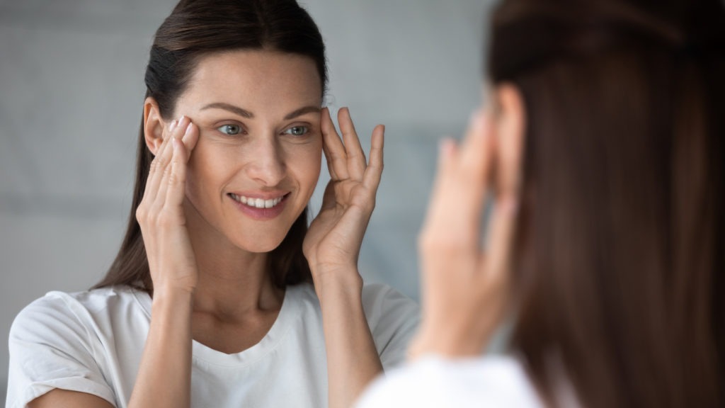 Picture of a woman looking happy while stretching skin below the eye area