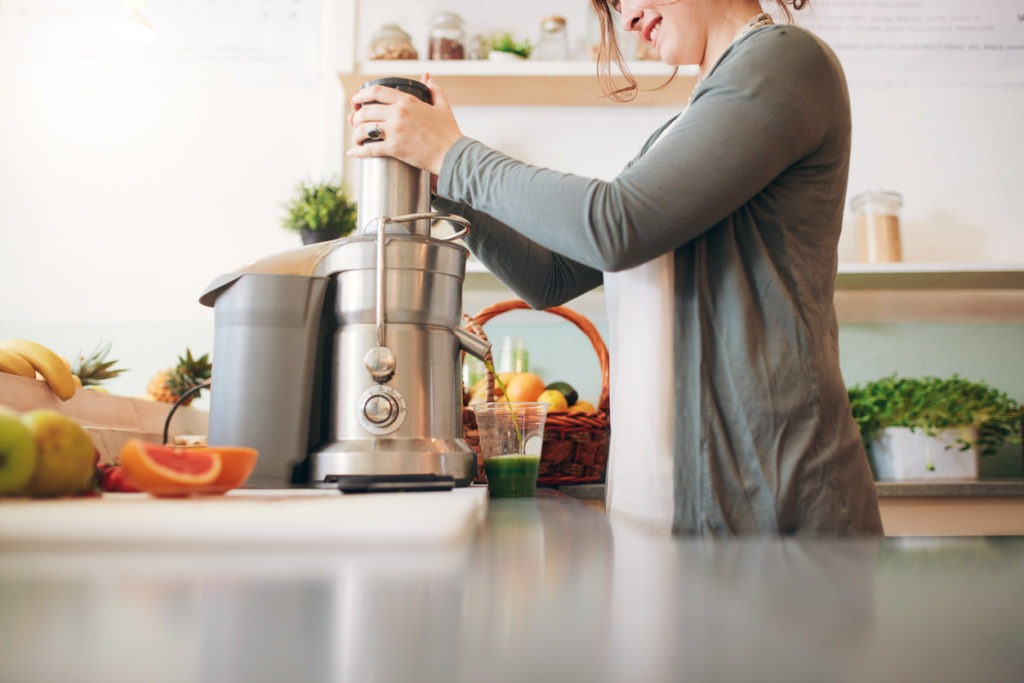 A woman preparing juice using a juicer